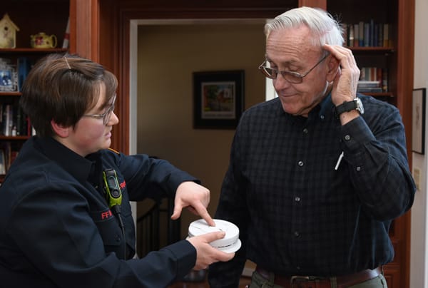 photo of firefighter testing smoke alarm with older adult