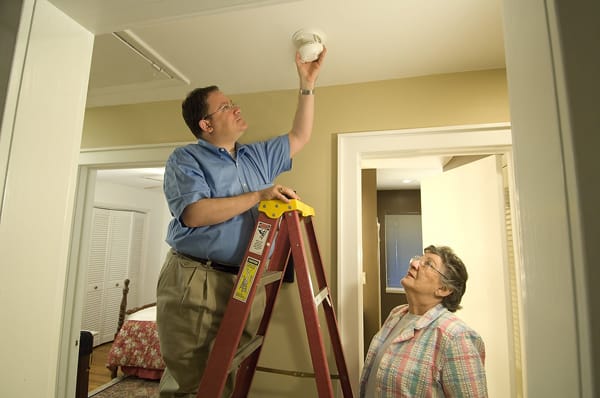 man installing a smoke alarm for an older adult