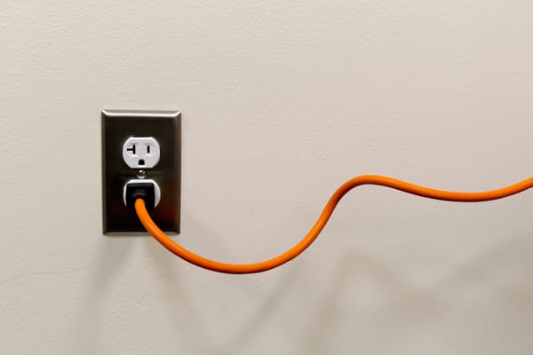 orange extension cord plugged into a wall outlet