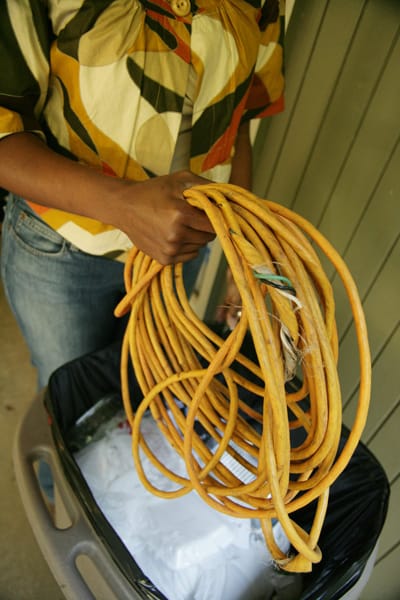 frayed electrical cord being thrown into a garbage can