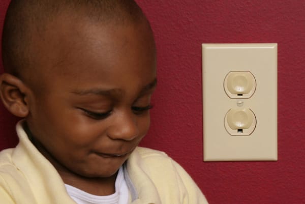 boy next to electrical outlet with covers