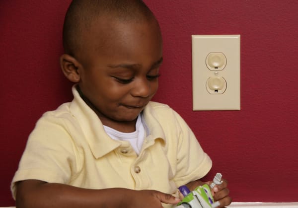 boy next to electrical outlet with covers