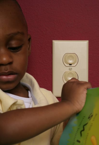 boy next to electrical outlet with covers