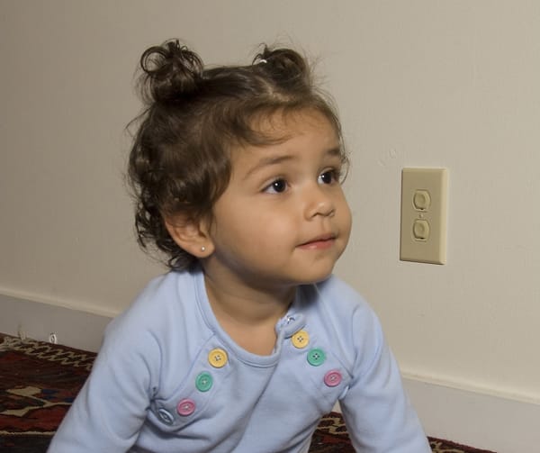 girl next to electrical outlet with covers
