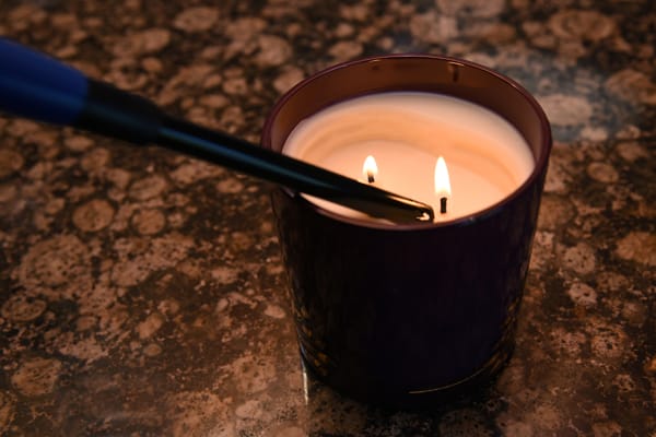 closeup of a candle on a counter being lit by long-arm lighter