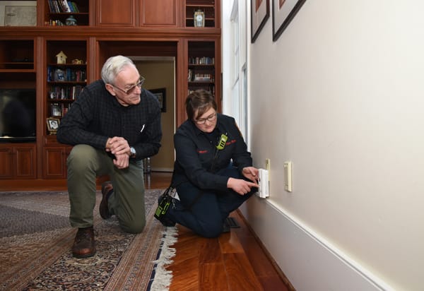 firefighter showing older adult how to test a CO alarm