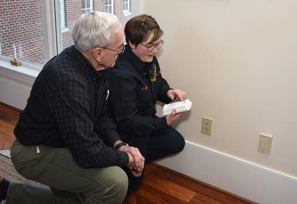 firefighter showing older adult the back of a CO alarm