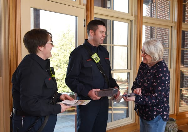 two firefighters laughing with an older woman