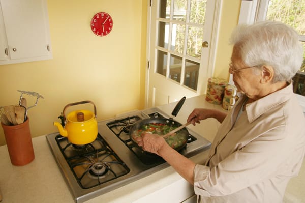 older woman frying vegetables on the stove