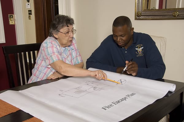 firefighter and older adult reviewing a fire escape plan