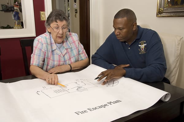 firefighter helping an older adult make a fire escape plan