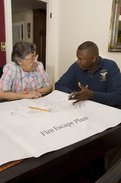 firefighter helping an older adult make a fire escape plan