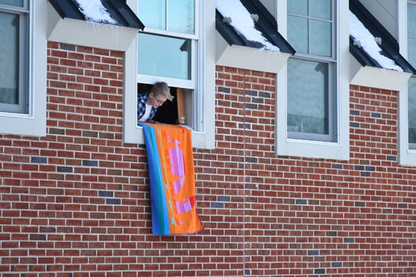 boy practicing to hang a towel out of his window to alert firefighters