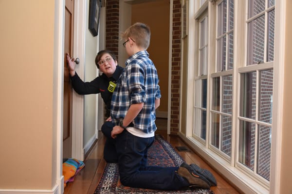 a firefighter showing a boy how to feel if a door is hot