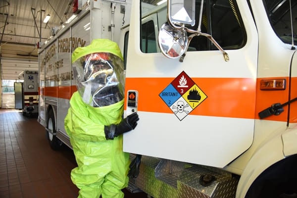 firefighter in hazmat suit getting into a hazmat unit