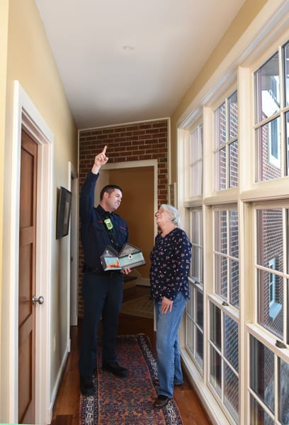 male firefighter standing beside man and pointing to a sprinkler head on the ceiling