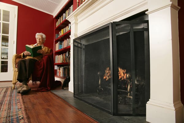 older woman sitting next to a fireplace