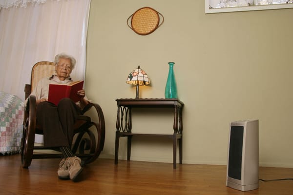 older woman sitting 3 feet away from a portable heater