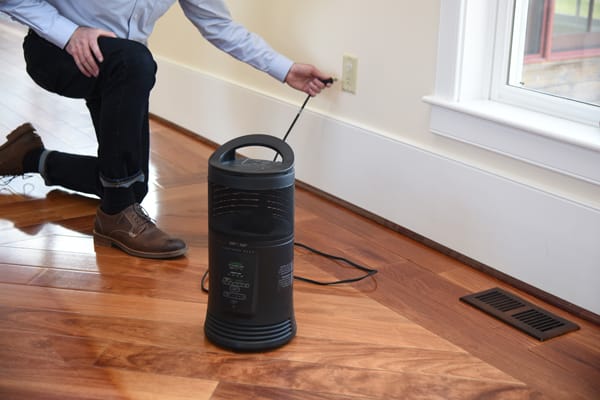 man plugging portable heater into electrical outlet