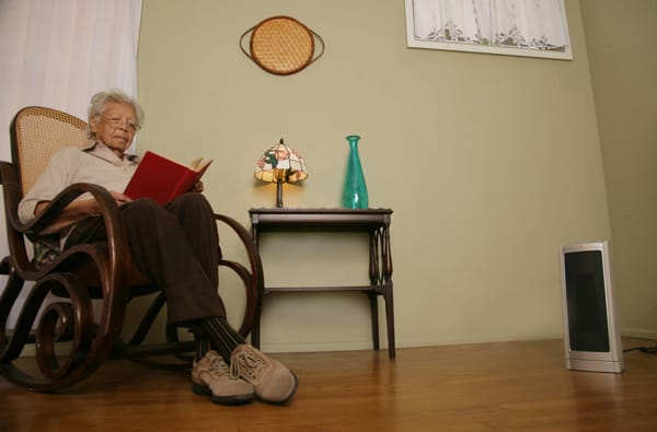 older woman sitting 3 feet away from a portable heater
