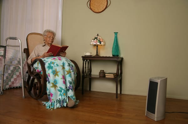 older woman sitting 3 feet away from a portable heater