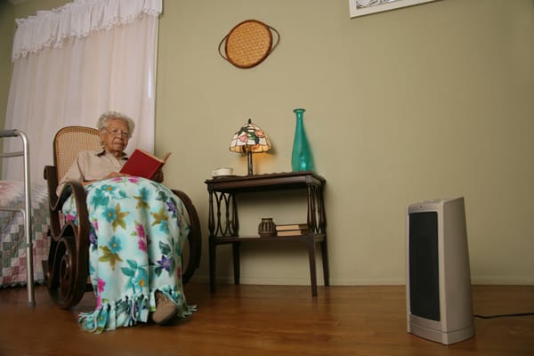 older woman sitting 3 feet away from a portable heater