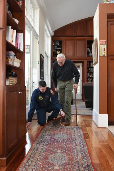 firefighter pointing out a rug trip hazard to an older adult