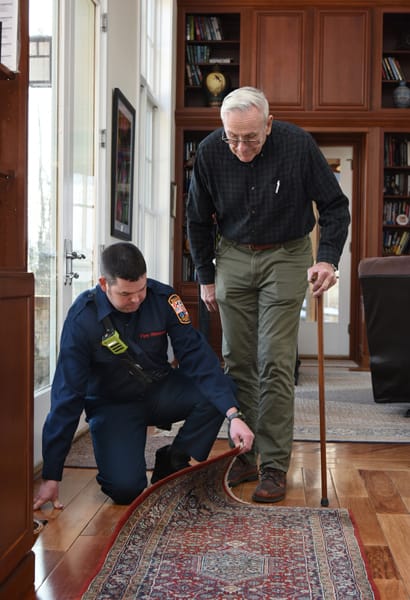 firefighter pointing out a rug trip hazard to an older adult