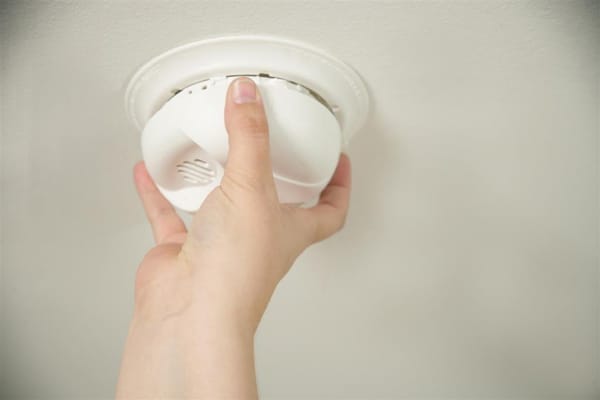 closeup of hand reaching to install a smoke alarm