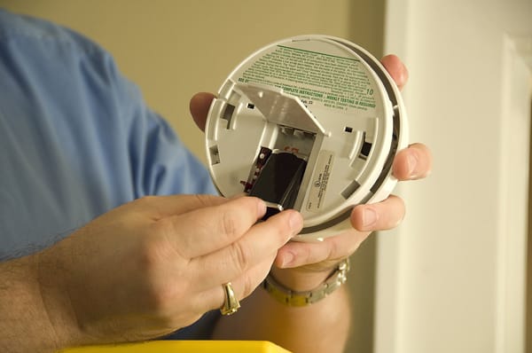 closeup of hand removing a smoke alarm battery