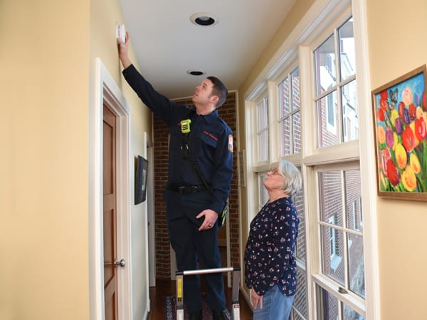 firefighter testing smoke alarm for older woman