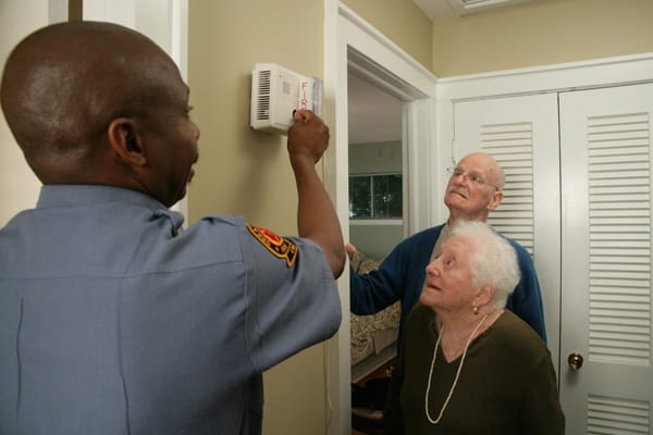 firefighter showing older adults a smoke alarm for the hearing impaired