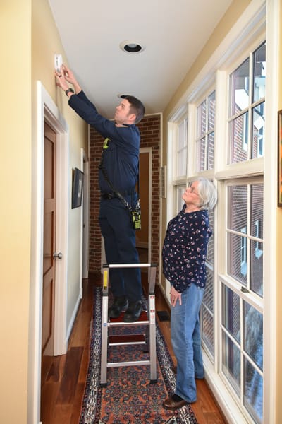 firefighter testing smoke alarm for older woman