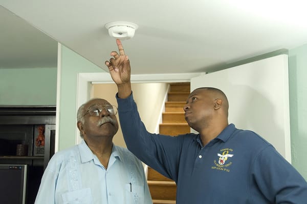 firefighter and an older man testing a smoke alarm