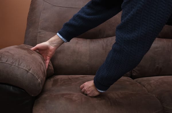 hands checking between sofa cushions for dropped cigarettes