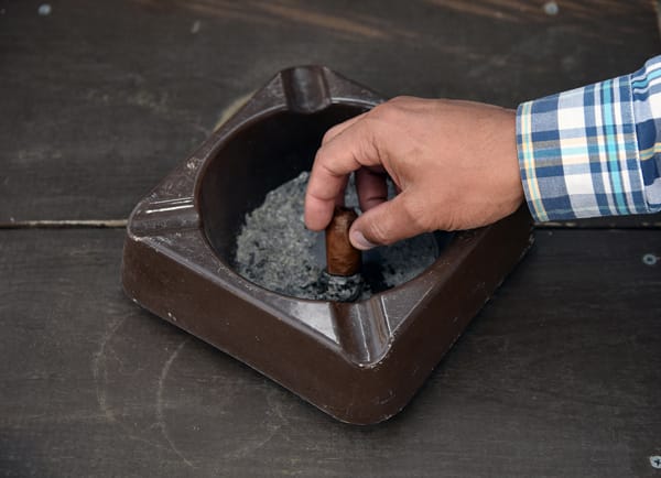 closeup of hand extinguishing cigar in an ashtray