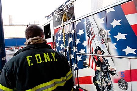 FDNY firefighter next to a fire engine painted with a 9/11 tribute