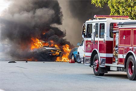 fire engine in foreground, cars on fire in background