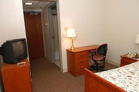 dorm room showing dresser, tv, desk and bed