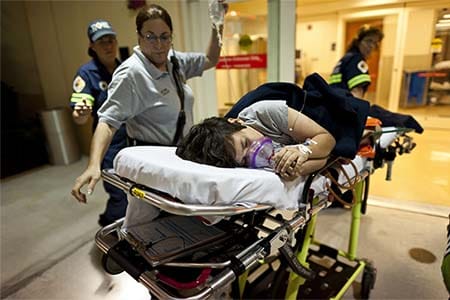 EMTs leading patient on stretcher into the emergency department