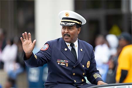 African American fire chief riding in a car at a parade