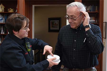 firefighter testing a smoke alarm for older adults