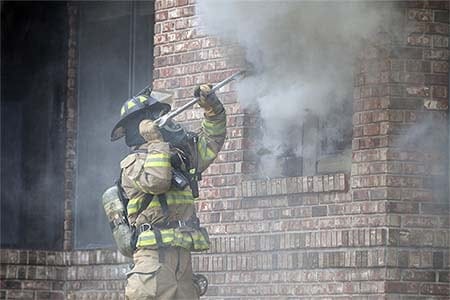 firefighter using a halligan bar in a smokey environment