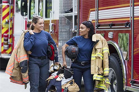photo of two firefighters carrying gear and talking
