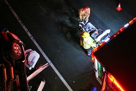 firefighters putting patient into an ambulance at the scene of a car accident after dark