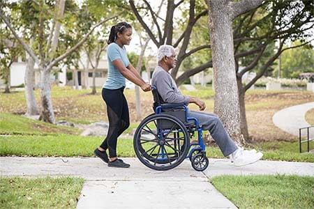 caregiver pushing a man in a wheelchair