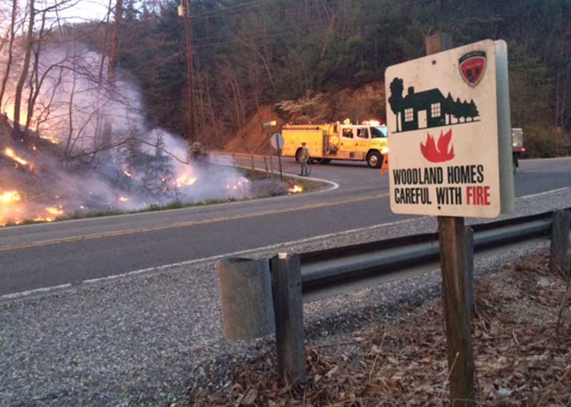 a brush truck on the side of a road where a wildfire is burning
